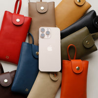 A collection of leather phone pouches in various colors displayed together with a white smartphone placed on top.