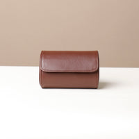 A pebble brown, oval-shaped, two-slot watch case with a snap closure, made of premium leather.