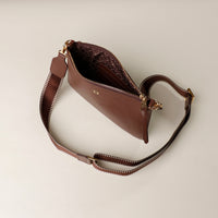 Brown leather handbag with a strap on a light beige background