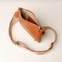Brown handbag with a textured strap on a light background