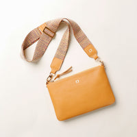 Yellow handbag with a textured strap on a light background