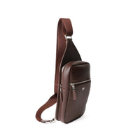 Side view of a chocolate brown sling pack andres with a silver zipper and the Danilos logo over a white background