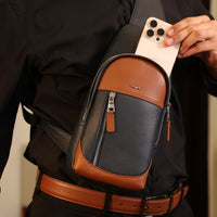 Man using a Danilos leather sling packs Andres bags with silver zippers sliding a phone on a beige background