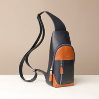 Side view of three Danilos leather sling pack Andres on a marine blue and brown color with silver zippers on a beige background