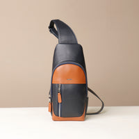 Front view of a Danilos leather sling pack Andres in a marine blue and brown colors with silver zippers on a beige background