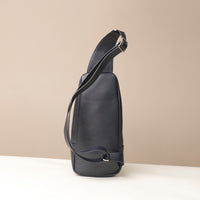 Back view of an open Danilos leather sling pack, Andres in a marine color with silver zippers on a beige background