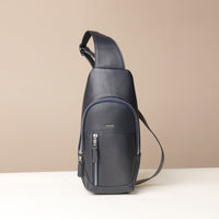 Front view of an open Danilos leather sling pack, Andres in a marine color with silver zippers on a beige background