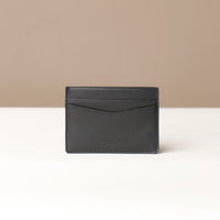 Black leather cardholder on a beige background