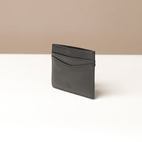 Black leather cardholder on a white surface with a beige background