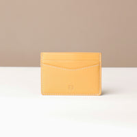 A yellow leather card holder with multiple slots, displayed against a neutral background.