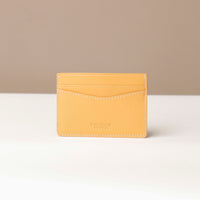 Yellow cardholder on a white surface with a beige background