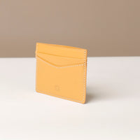 Yellow cardholder on a white surface with a beige background