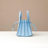 Light blue handbag with thin straps on a beige background