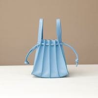 Light blue bucket bag with straps on a beige background