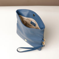 Upper view of an open blue leather Karelia Clutch Danilos with a visible hand strap over a white and beige background
