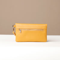 Back view of a yellow leather Karelia Clutch Danilos with a visible gold zipper over a white and beige background