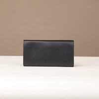 back view of a danilos clucth versaviva in black leather in a beige background