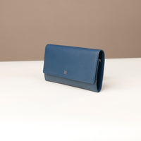 side view of a danilos clucth versaviva in navy blue leather in a beige background