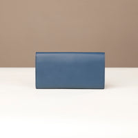 back view of a danilos clucth versaviva in navy blue leather in a beige background