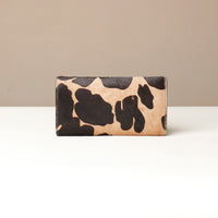Cow print hair on leather Danilos wallet on a beige background