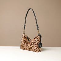 Leopard print crossbody Danilos bag with black handle on a beige background