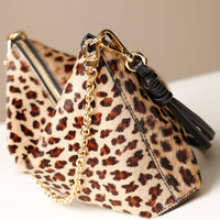 close-up Leopard print crossbody Danilos bag with gold chain and black tassel on a neutral background