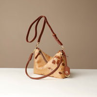 Brown leather crossbody Danilos bag with a cowhide pattern on a beige background