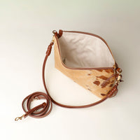 upper view, opened Brown leather crossbody Danilos bag with a cowhide pattern on a light background