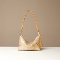 Gold and yellow crossbody Danilos bag with a textured snake surface on a beige background