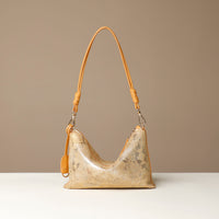 Gold and yellow crossbody Danilos bag with a textured surface on a beige background