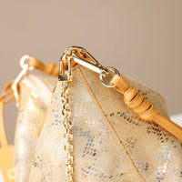 Close-up of a gold Danilos handbag with a chain detail on a neutral background