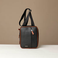 front view of a danilos black and brown crossbody dylan bag over a beige background