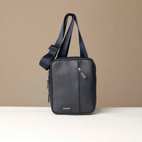 front view of a danilos navy blue crossbody dylan bag over a beige background
