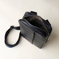 upper view of a open danilos navy blue crossbody dylan bag over a beige background