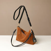 Brown Danilos suede handbag with black strap on a beige background
