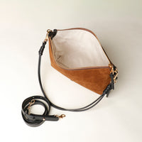 Brown Danilos leather handbag with black strap on a light beige background