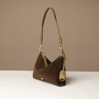 green suede Danilos handbag with gold accents on a beige background