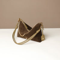 green suede Danilos handbag with gold chain detail on a white surface with a beige background