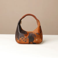 Brown hair on leather danilos  handbag with black spots on a beige background