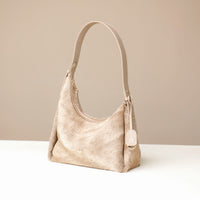 Beige hair on Danilos leather handbag on a white surface with a beige background