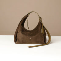 Brown suede handbag with a strap on a beige background