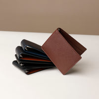 upper view of a Danilos pebble brown leather money clip Steven, over 5 money clips in a white background