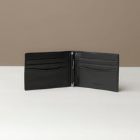 Front view of an open Danilos pebble marine black leather money clip Steven, with 6 card slots, in a beige background