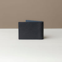 Back view of a Danilos pebble marine blue leather money clip Steven, in a beige and white background