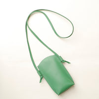 Green leather crossbody bag on a white background
