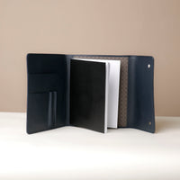 Open navy blue leather portfolio with interior pockets on a beige background