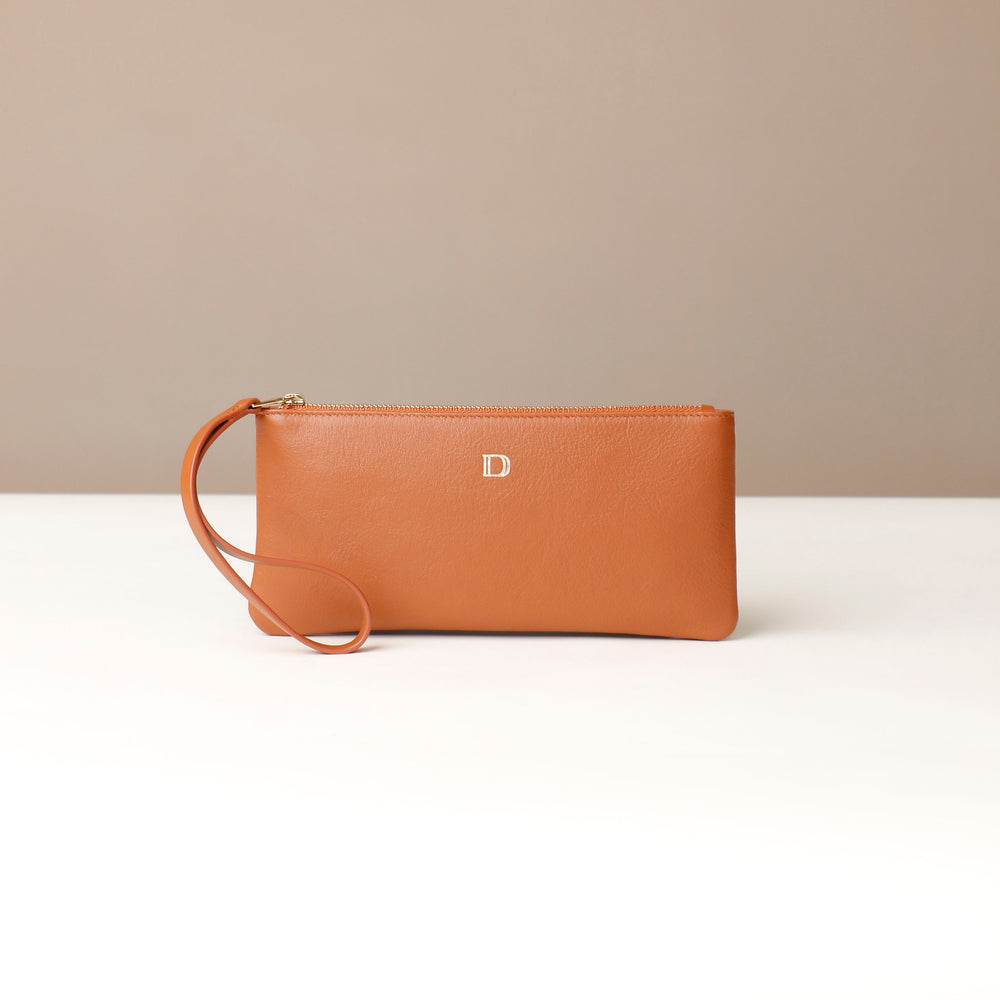 Brown leather clutch with a strap on a beige background